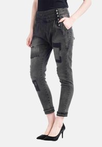 Grå denim joggers med hög midja, flera fickor, lappar och nitar vid fållen, kombinerat med svarta klackar.