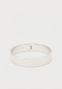 Ασημένιο βραχιόλι με λεία, στρογγυλή μορφή και γεωμετρικό σχέδιο. Διαθέτει κούμπωμα με μεντεσέ και γυαλιστερή επιφάνεια. Υφασμάτινη λεπτομέρεια κατά μήκος της επιφάνειας.