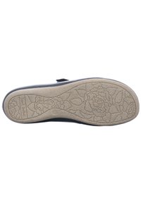 Suela de zapatos de goma beige claro con patrón floral. Parte superior azul marino con tira de velcro. Texturizada para agarre y estabilidad.