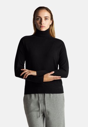 Schwarzer Rollkragenpullover aus weichem Material mit langen Ärmeln, taillierter Passform, und passenden grauen Jogginghosen mit elastischem Bund.