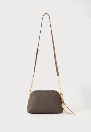 Καφέ τσάντα Michael Kors χιαστί με χρυσό λουρί αλυσίδα και λογότυπο φυλαχτό σε λευκό φόντο.