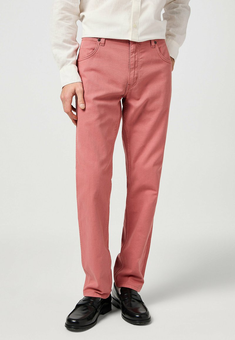 Pantaloni rosa chiaro con taglio dritto, realizzati in cotone, caratterizzati da un classico design a cinque tasche e cuciture a contrasto, abbinati a scarpe nere.