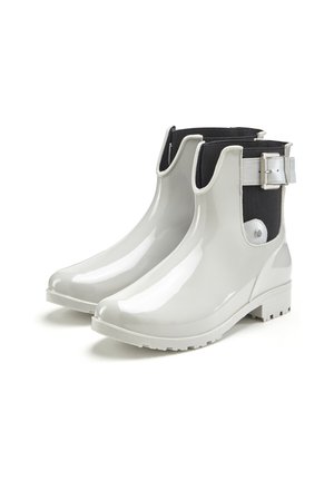 Weiße Gummistiefel mit glänzender Oberfläche, schwarzen Stoff-Seiteneinsätzen und einem silbernen Schnallenakzent. Texturierte Sohle für besseren Halt.