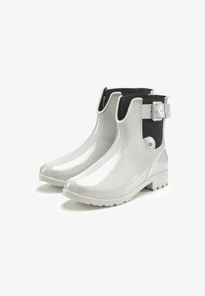 White rubber ankle boots with a glossy finish, black fabric side panels, and a silver buckle accent. Textured sole for grip.
