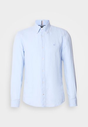 Chemise à manches longues bleu clair en tissu texturé, dotée d'un col boutonné et d'un petit logo sur la poitrine. Cinq boutons sur le devant.
