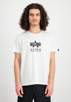 Weißes Baumwoll-T-Shirt mit einem abgenutzten schwarzen Logo, das "ALPHA INDUSTRIES" zeigt, kurzen Ärmeln und einem Rundhalsausschnitt.
