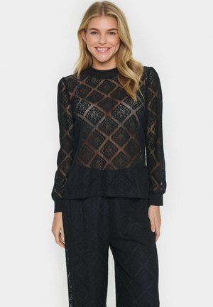 Black lace top with diamond pattern, long sleeves, and ribbed neckline. Paired with matching black lace pants. Sheer texture.