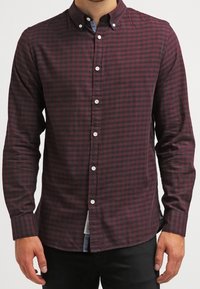 Camicia a maniche lunghe a quadri in bordeaux e blu navy, con colletto button-down, bottoni bianchi e orlo dritto con spacco laterale.