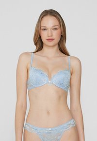 Light blue lace bra with molded cups, scalloped edges, and a decorative button at the center. Accompanied by matching lace thong.