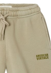 Beige joggingbroek met elastische tailleband en trekkoord, voorzien van zijzakken en het "American Vintage"-logo bedrukt vlakbij de zak.