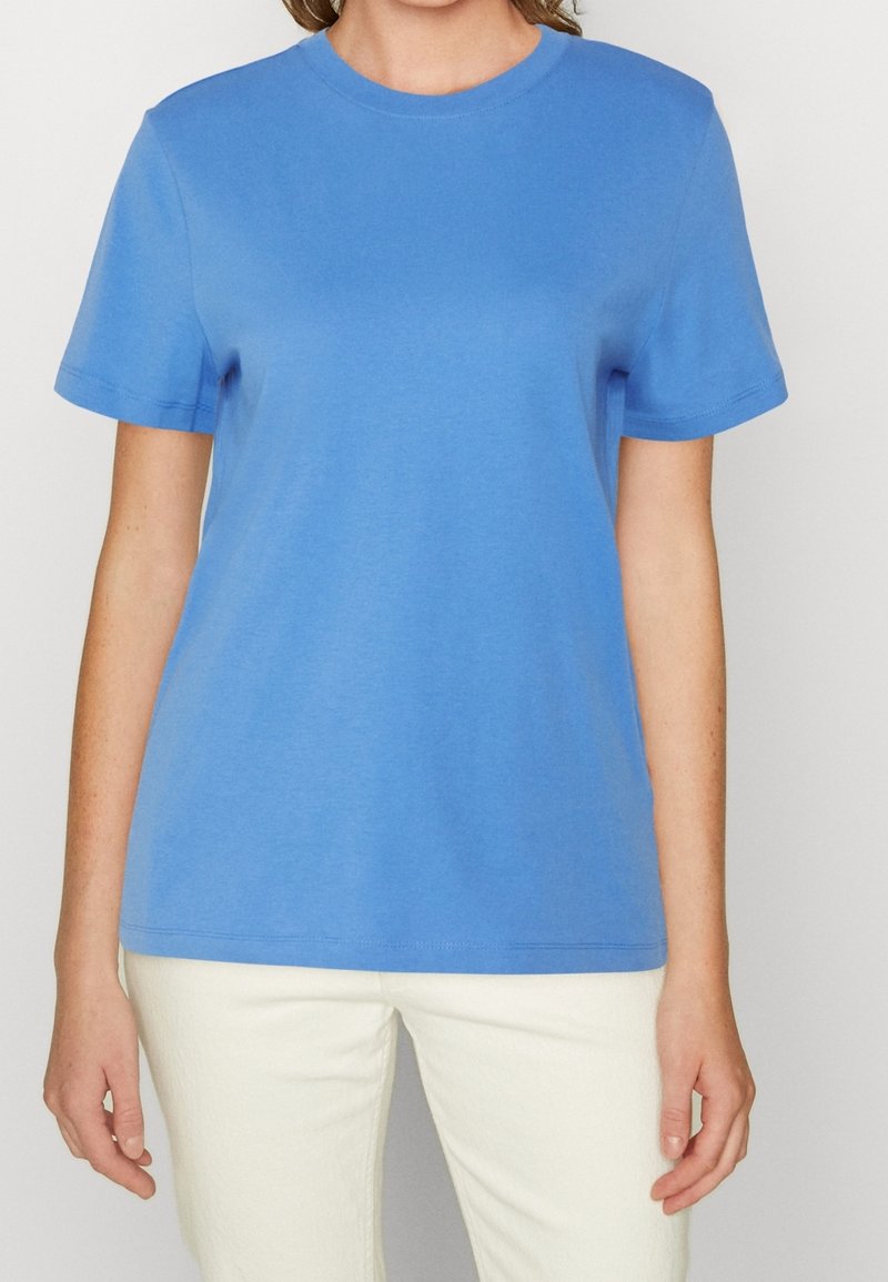 Světle modré bavlněné tričko s kulatým výstřihem a krátkými rukávy, které se vyznačuje hladkou texturou a uvolněným střihem.