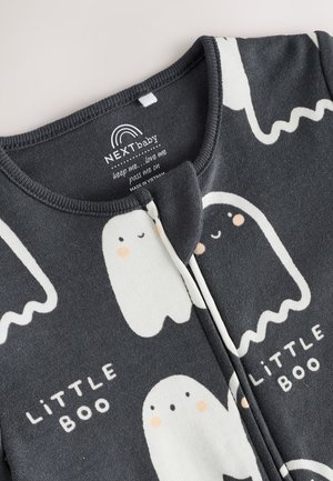 Pijama negro con patrones de fantasmas blancos; lleva el texto "PEQUEÑO FANTASMA." Tela suave, escote redondeado y cierre de cremallera delantero.