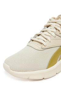 Smėlio spalvos sportiniai batai su tekstūruotu akių viršumi, šviesesnio atspalvio sintetikinėmis detalėmis ir plokščiais raišteliais. Apvali nosis ir paminkštintas padas.