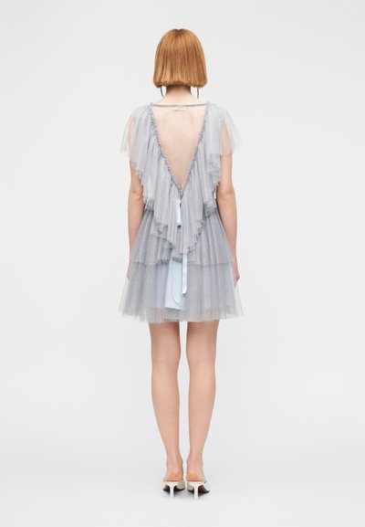 Κοντό γκρι φόρεμα από τούλι με στρώσεις βολάν, βαθιά V-πλάτη και ανοιχτό μπλε εσωτερική στρώση. Ο σχεδιασμός περιλαμβάνει διάφανο ύφασμα και λεπτομέρεια με δέσιμο.