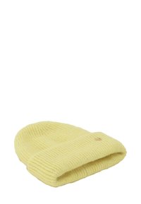 Miękki, żółty dziany kapelusz z podwiniętym brzegiem i małym okrągłym metalowym logo z boku.