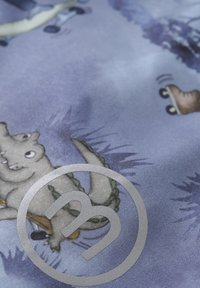 Tissu bleu avec des dinosaures et des escargots de style cartoon ; ajoute un élément ludique. Un grand logo circulaire gris est centré dans l'image.