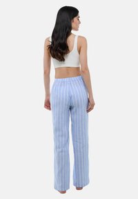 Pantalons larges à rayures bleu clair avec une taille élastique. Fabriqués en tissu doux, ils présentent de fines rayures verticales blanches pour un détail supplémentaire.