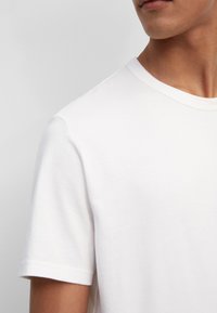 Witte katoen crew neck t-shirt met korte mouwen, gladde textuur, subtiele stiksels bij de nek en een ontspannen pasvorm.