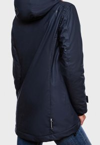 Chaqueta impermeable azul marino con capucha, con una textura suave y una marca sutil. Cuerda ajustable en el dobladillo y en los puños.