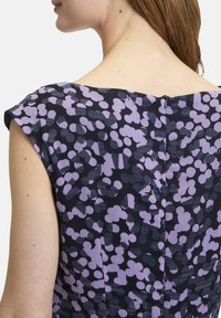 Ärmelloses Kleid mit einem lila und schwarzen abstrakten Muster; strukturierter Stoff; runder Ausschnitt; Reißverschlussdetail auf dem Rücken; glatte Oberfläche des Materials.