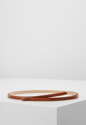Ceinture fine en cuir marron enroulée à plat sur une surface blanche contre un fond gris clair uni.