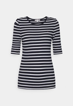 Tummansinivalkoinen, vaakaraitainen, lyhythihainen paita pyöreällä pääntiellä ja pienellä logolla vasemmassa rinnassa.