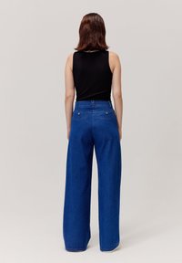 Spodnie dżinsowe o szerokich nogawkach w kolorze niebieskim, z wysokim stanem, solidnym materiałem, dwiema tylnymi kieszeniami oraz kontrastowymi detalami przeszyć.