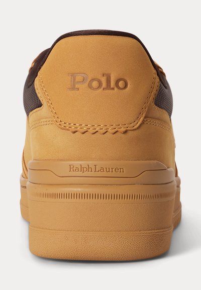Πίσω όψη μιας μπεζ αθλητικής παντόφλας Polo Ralph Lauren με ανάγλυφο λογότυπο Polo στην ταμπέλα της φτέρνας και Ralph Lauren στη μεσαία σόλα.