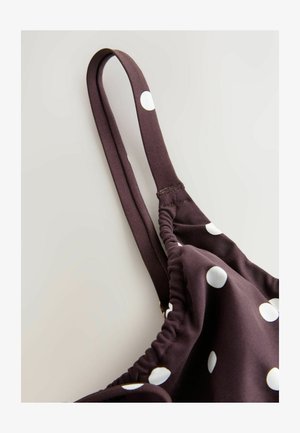 Material maro cu buline albe, cu bretele subțiri și detalii adunate. Textură netedă, vedere parțială laterală.