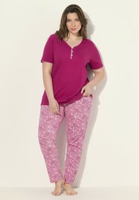 Magenta t-shirt met knoopdetails, gecombineerd met roze paisley-gepatteerde broek. Zachte stof, relaxte pasvorm en lichtgewicht ontwerp.