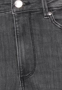 Jeans de ganga pretos com um design clássico de cinco bolsos, fecho de botão metálico e detalhes de costura discretos ao longo das costuras.