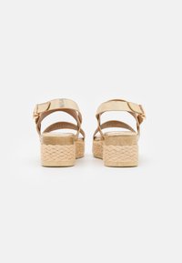 Sandales dorées à lanières avec une plateforme et un talon en jute tressé. Dotées d'une bride de cheville métallique avec une boucle et une finition texturée.