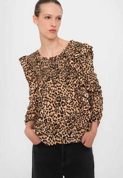 Luipaardprint blouse met ruffels aan de mouwen, gathered detail bij de halslijn en een gestructureerde stof. Gecombineerd met zwarte jeans.