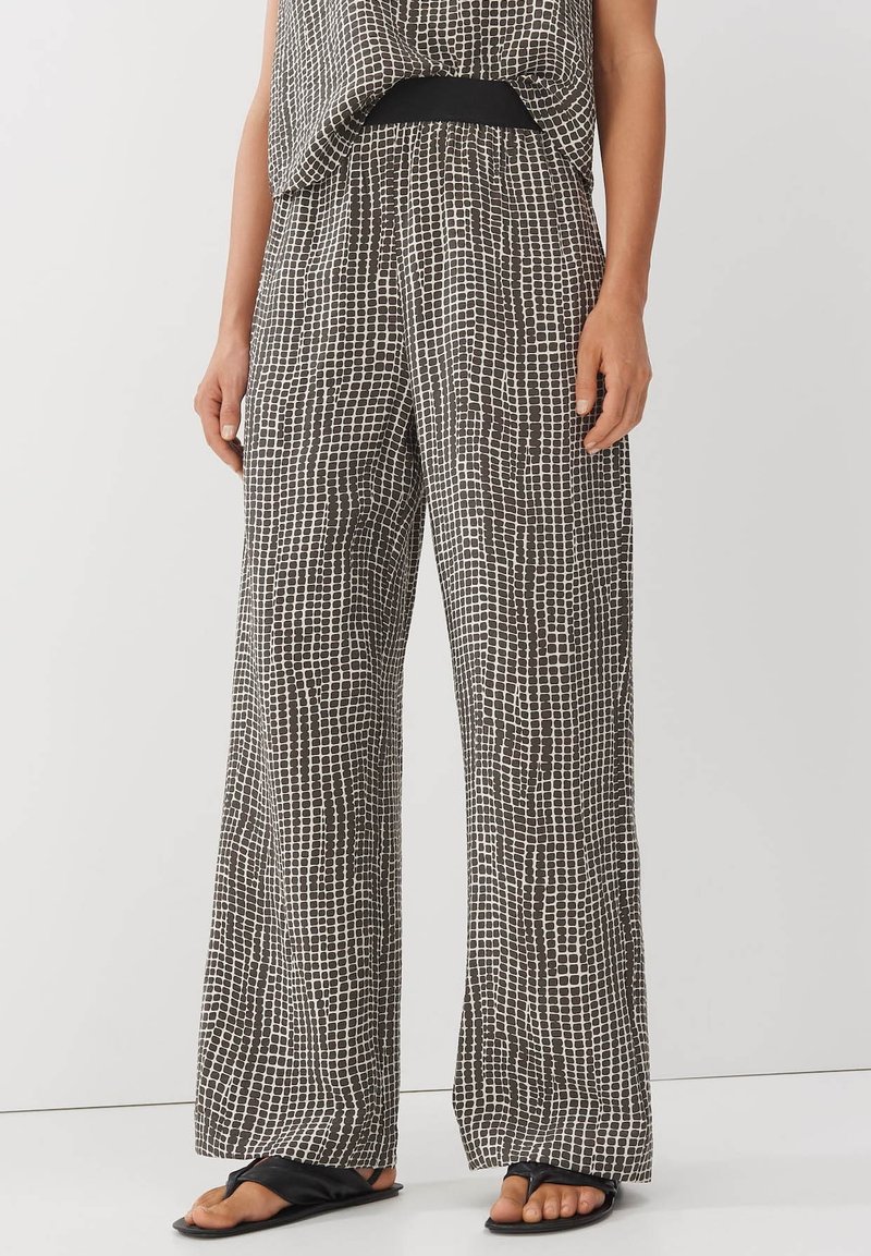 Losse, zwart-wit gemusterde broeken met een ruitpatroon, voorzien van een elastische tailleband en wijde pijpen, gemaakt van een lichtgewicht stof.