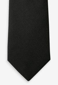 Corbata de etiqueta con un patrón texturizado, que presenta un extremo estrecho y puntiagudo. La tela parece suave con un sutil brillo.