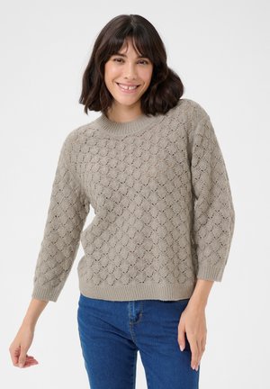 Cappotto a maglia grigio chiaro con un motivo a onda testurizzato, scollatura rotonda e maniche a tre quarti. Abbinato a jeans di denim blu.