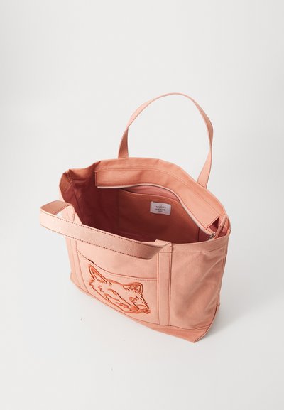 Ροζ βαμβακερή τσάντα tote με ανάγλυφο σχέδιο αλεπούς στο μπροστινό μέρος, διαθέτει δύο χερούλια και εσωτερική τσέπη με φερμουάρ. Λείος υφασμάτινος χαρακτήρας.