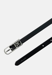 Zwarte leren riem met een zilveren geometrische gesp. De riem heeft gaatjes voor aanpassing en een gladde, gestructureerde afwerking.