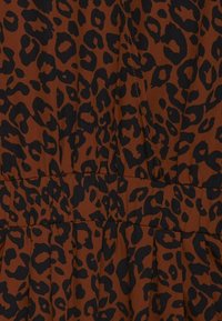 Brunt tyg med ett svart leopardtrycksmönster, med en smockad midja och veck, vilket skapar en texturerad look.