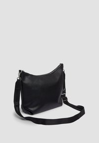 Schwarze, strukturierte Leder-Crossbody-Tasche mit verstellbarem Stoffriemen und silbernem Zubehör auf plain grauem Hintergrund.