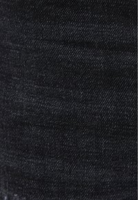 Tejido de denim oscuro con una textura suave y un patrón de sarga visible. El color es un negro profundo sólido con una mínima decoloración.