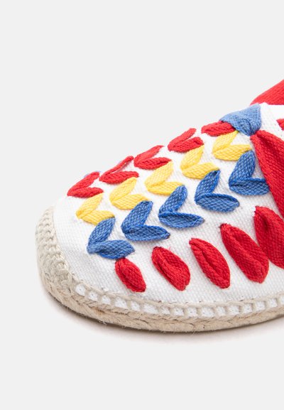 Balti austos medžiagos batų pora su raudonomis, geltonomis ir mėlynomis megztomis lapų raštais ir pintu jūržolių padu.