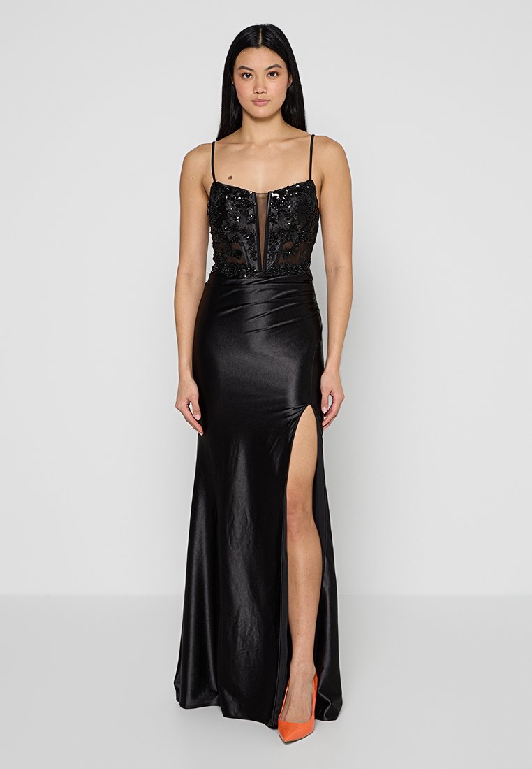 Abito da sera nero con corpetto decorato di paillettes, pannelli trasparenti e uno spacco alto. Tessuto di raso liscio; presenta spalline sottili e una silhouette aderente.