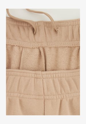 Beige sweatpants met een zachte binnenvoering, elastische tailleband en trekkoord. De stof heeft een gladde textuur met zichtbare stikdetails.