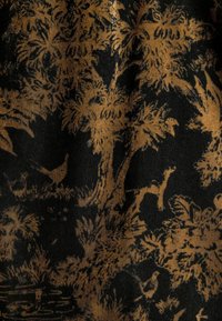 Tissu noir mettant en avant un motif détaillé et texturé de feuillage marron, d'arbres et d'oiseaux, montrant des designs complexes tout au long.