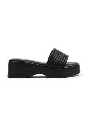 Sandalias de plataforma negras con una correa texturizada y acanalada y una plantilla suave; suela gruesa y curvada con un acabado madera.