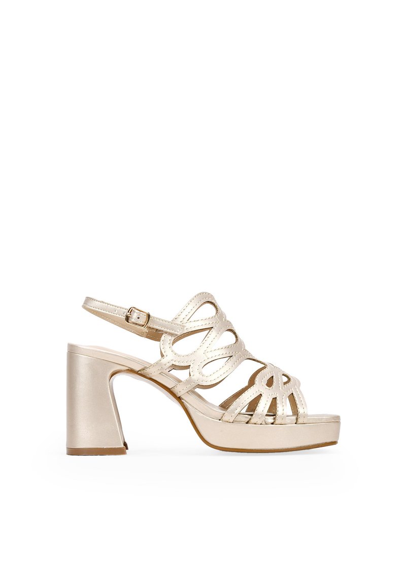 Metallic gold high-heeled sandal with open toe, crisscross strap design, ankle buckle, and stacked block heel. Smooth texture and shine.