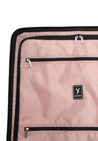 Organizzatore da valigia rosa in tessuto con tre cerniere nere visibili e una patche in bianco e nero con il logo Suri Frey.