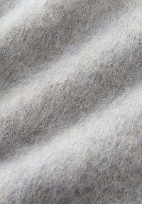Close-up van zacht, lichtgrijs wolweefsel met fijne vezels en een getextureerd, iets golvend oppervlak.