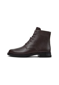 Stivaletti alla caviglia in pelle marrone con texture liscia, punta arrotondata e design con sei occhielli per i lacci. Caratterizzati da un tacco basso in gomma nera.